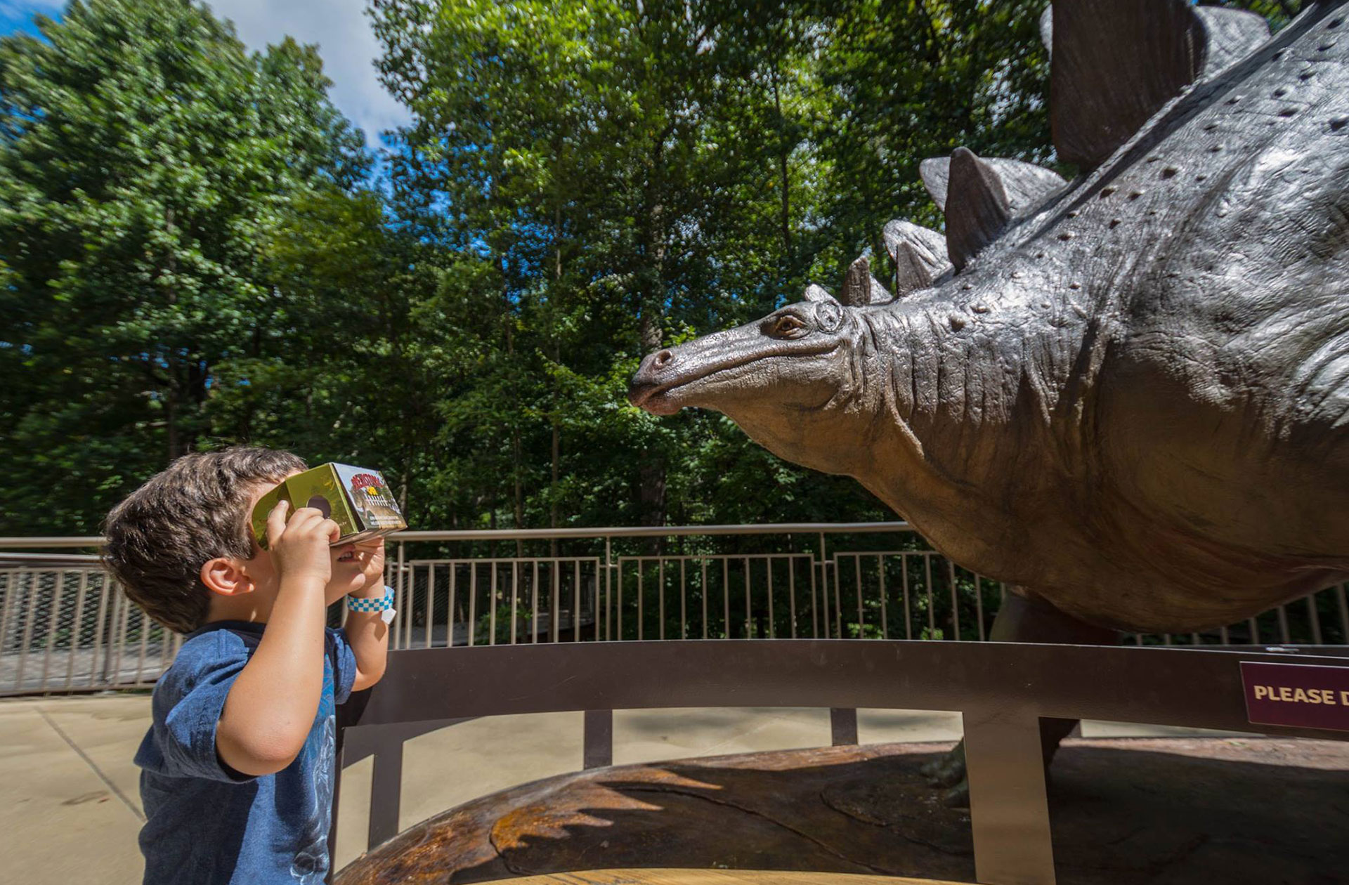 A child exploring a dinosaur through a mobile viewer